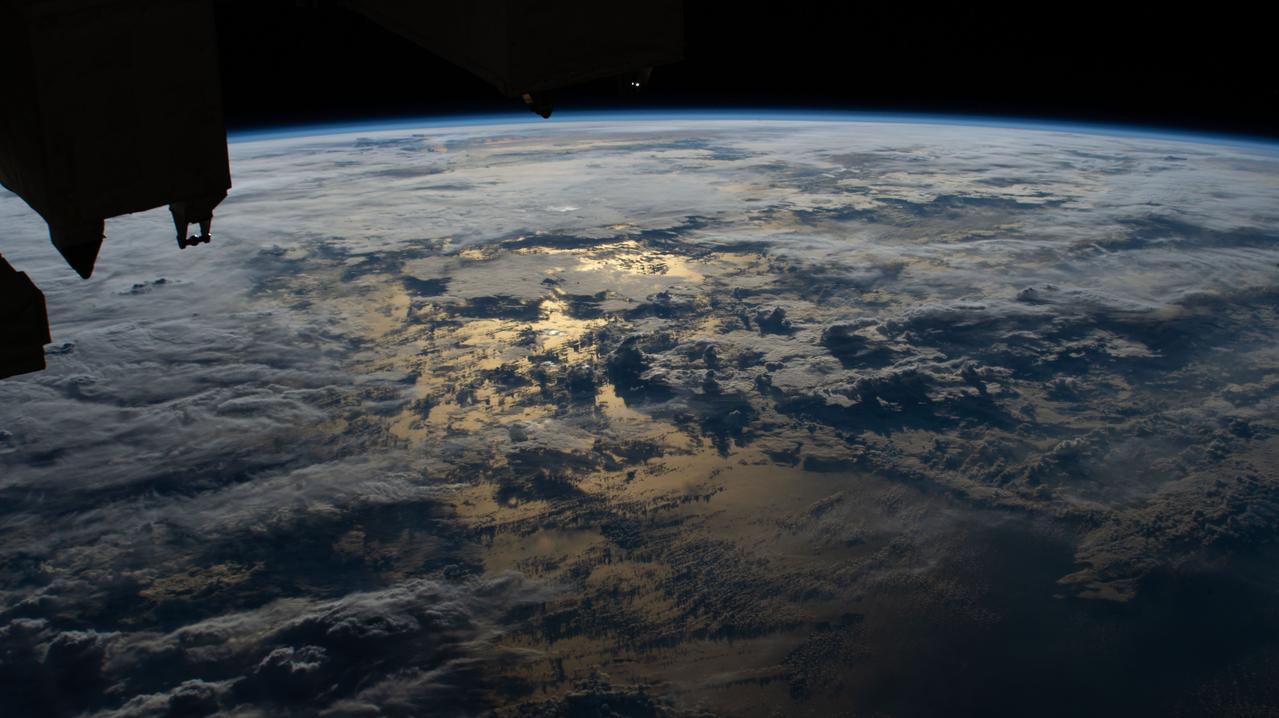 iss063e027862 (June 13, 2020) --- The sun's glint on the Timor Sea between Indonesia and Australia is mellowed by cloud cover in this photograph from the International Space Station.