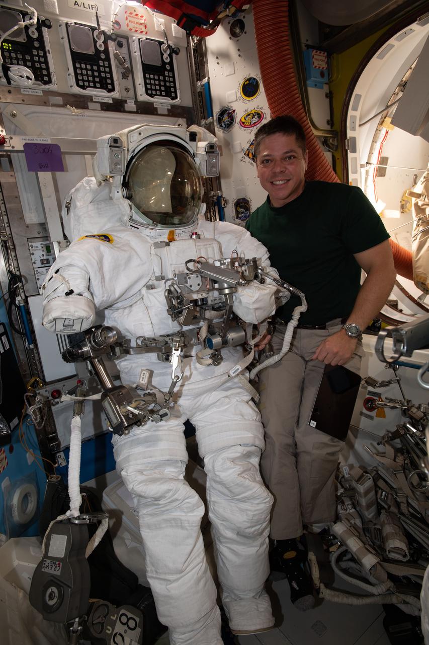 iss063e028016 (June 13, 2020) --- NASA astronaut and Expedition 63 Flight Engineer Bob Behnken poses with a U.S. spacesuit he is preparing for two spacewalks planned for June 26 and July 1 to upgrade power systems on the International Space Station.