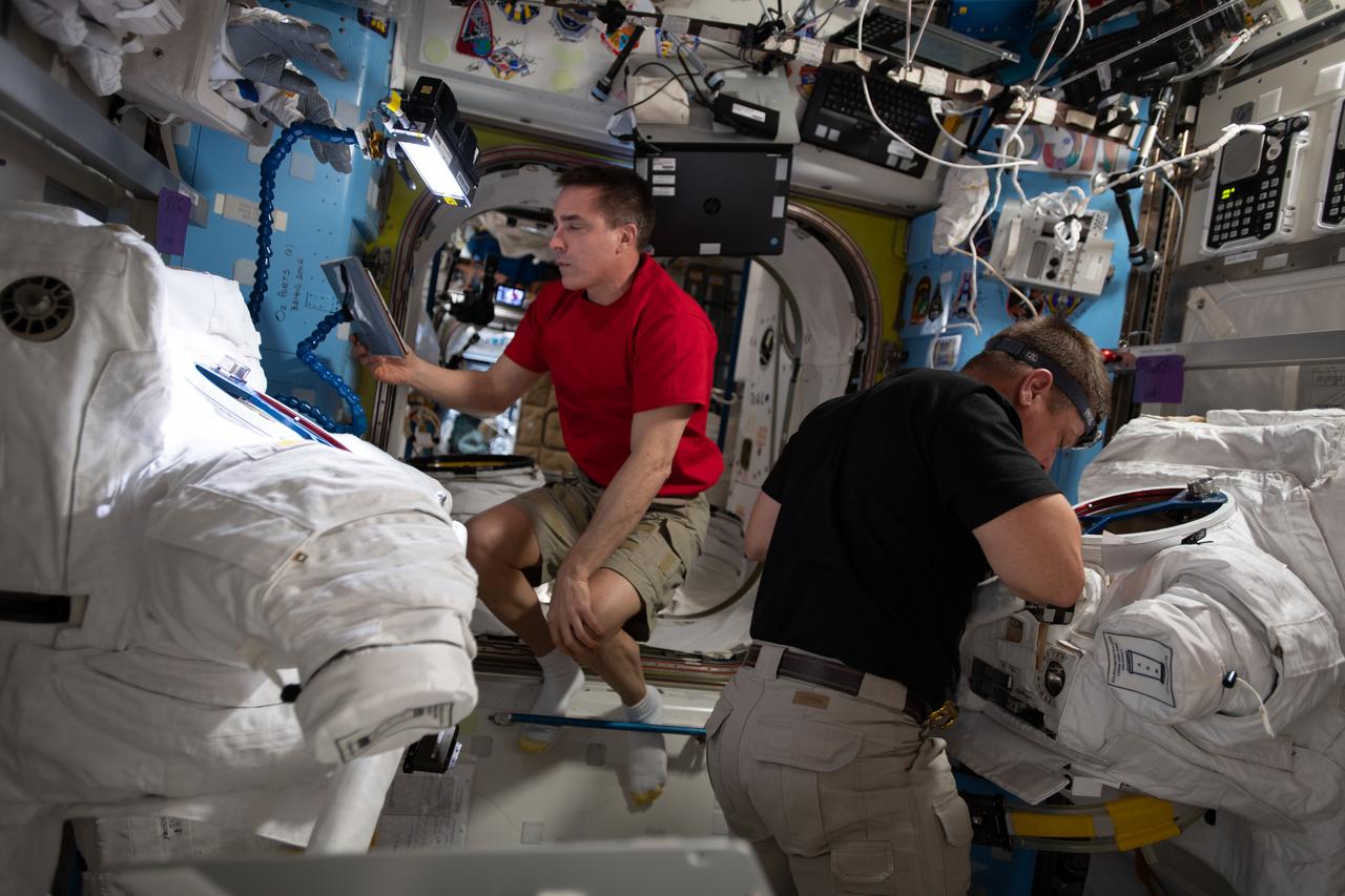 iss063e030599 (June 18, 2020) --- (From left) Expedition 63 Commander Chris Cassidy and Flight Engineer Bob Behnken work on U.S. spacesuit maintenance inside the International Space Station's Quest airlock.