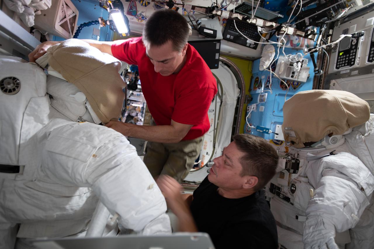 iss063e030609 (June 18, 2020) --- NASA astronauts (from top) Chris Cassidy and Bob Behnken work on U.S. spacesuits inside the International Space Station's Quest airlock.