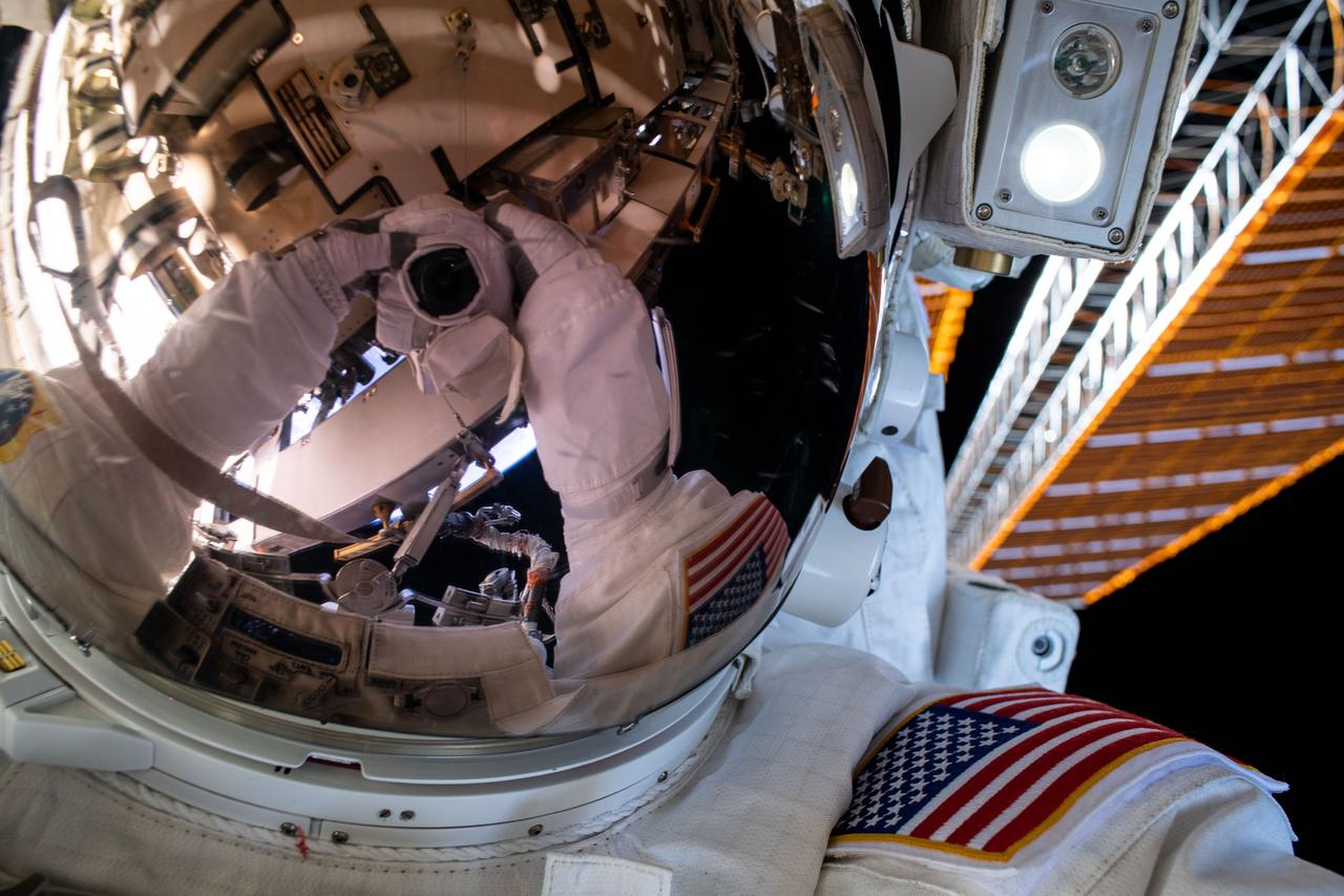 iss063e033403 (June 26, 2020) --- A spacewalker's spacesuit gloves and camera are reflected in the helmet visor in this "space-selfie" taken during a six-hour and seven-minute spacewalk.