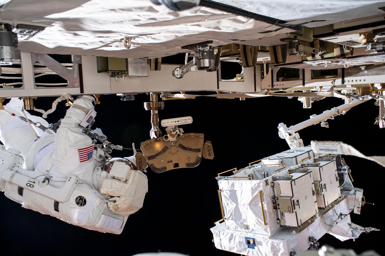 iss063e033414 (June 26, 2020) --- NASA astronaut Bob Behnken (at left) is pictured during a spacewalk to swap batteries and upgrade power systems on the International Space Station's Starboard-6 truss structure. Pictured at lower right, is an external pallet, gripped by the Canadarm2 robotic arm, that housed the batteries replaced on the orbiting lab. Behnken was joined during the six-hour and seven-minute excursion by NASA astronaut Chris Cassidy (out of frame).