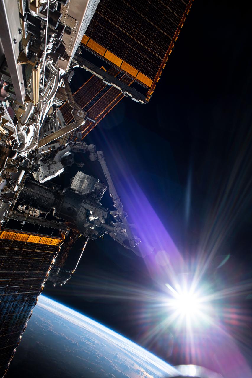 iss063e052528 (July 21, 2020) --- The sun beams just above the Earth's horizon as NASA astronaut and Expedition 63 Commander Chris Cassidy (center left) conducts his fourth spacewalk this year at the International Space Station. Cassidy has completed 10 spacewalks throughout his career for a total of 54 hours and 51 minutes spacewalking time.