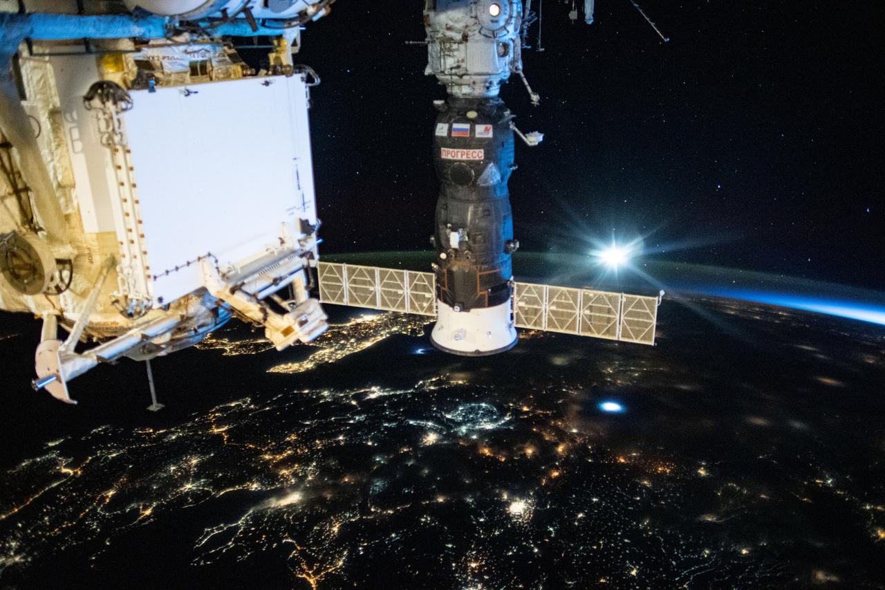 iss063e058352 (July 24, 2020) --- Russia's Progress 76 resupply ship is pictured docked to the International Space Station's Pirs docking compartment. Below the orbiting lab are the city lights of southeastern Europe with the boot of Italy towards the center. In the left foreground, is the Rassvet mini-research module that also serves as a docking port for Russian cargo and crew ships.