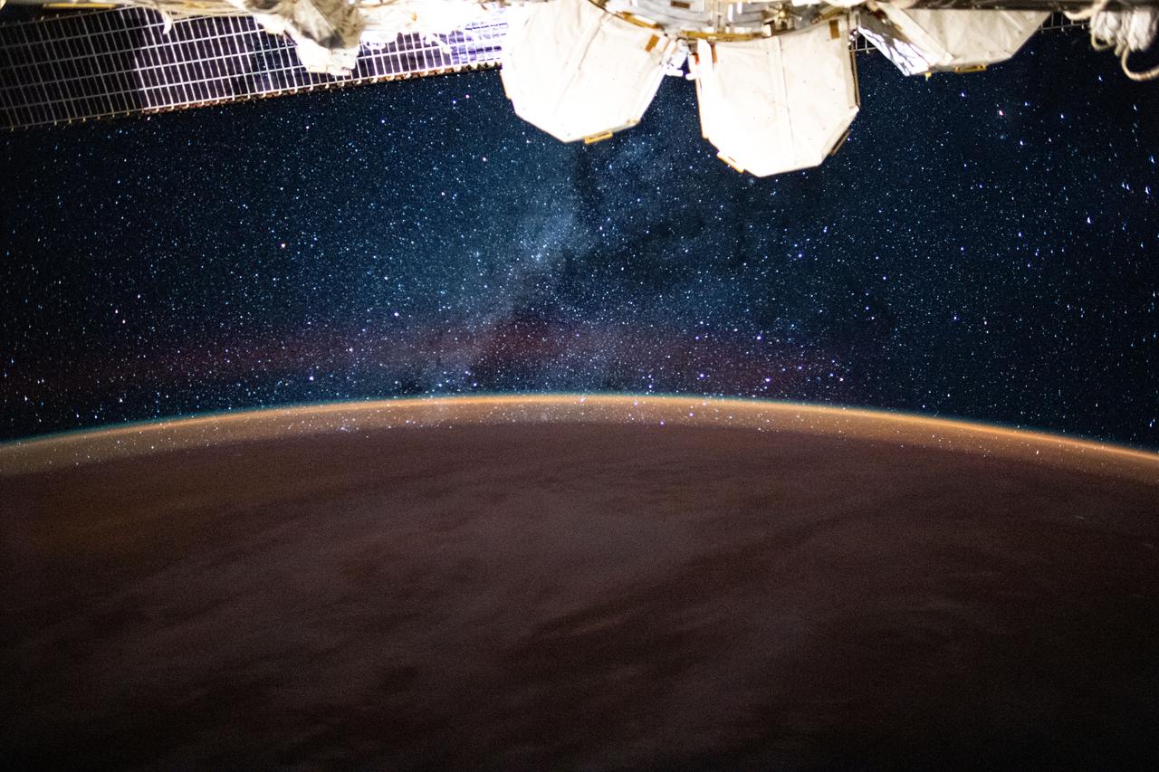 iss063e058409 (July 24, 2020) --- This long-exposure photograph from the International Space Station was taken during an orbital night period and reveals the Milky Way glittering above a bright but exaggerated atmospheric glow blanketing the Earth's horizon.