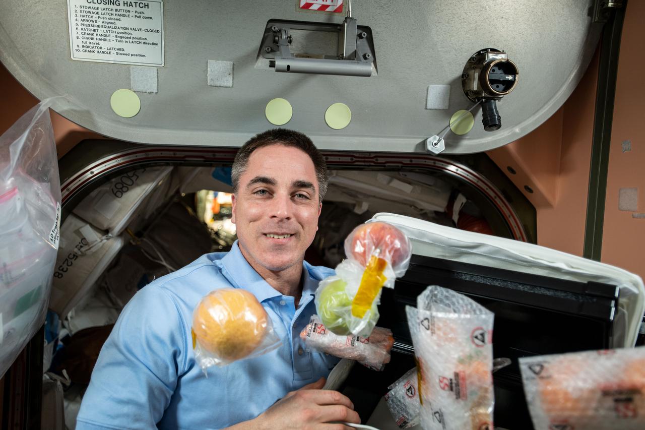 iss063e103926 (Oct. 5, 2020) --- NASA astronaut and Expedition 63 Commander Chris Cassidy unpacks fresh fruit and other food items shipped aboard the Northrop Grumman Cygnus space freighter to the International Space Station.