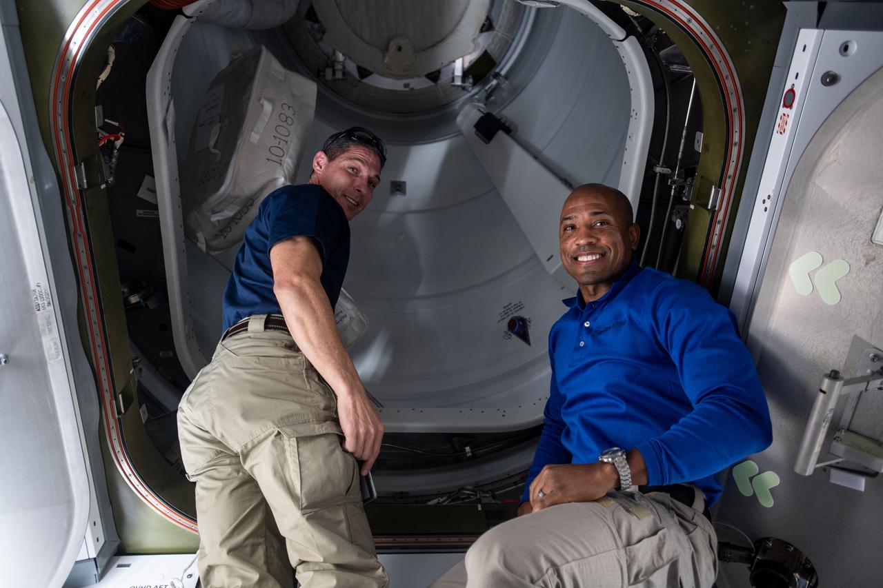 iss064e011087 (Dec. 7, 2020) --- NASA astronauts (from left) Michael Hopkins and Victor Glover are pictured in the vestibule between the Harmony module and the International Docking Adapter-3 before opening the hatch to the newly docked SpaceX Cargo Dragon vehicle.