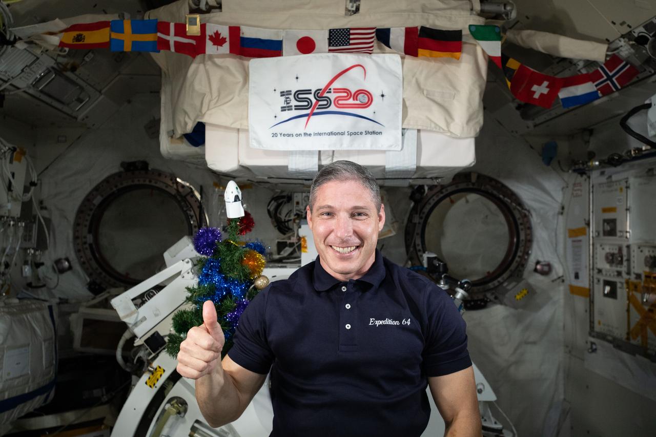iss064e013898 (Dec. 18, 2020) --- NASA astronaut and Expedition 64 Flight Engineer Michael Hopkins poses for a holiday season portrait with a Christmas tree inside Japan's Kibo laboratory module.