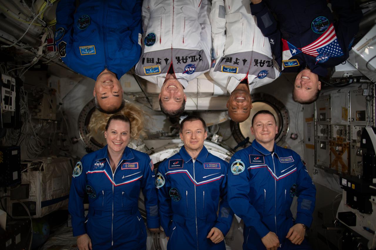 iss064e020871 (1/6/2021) --- The seven-member Expedition 64 crew poses for a portrait inside the International Space Station's Kibo laboratory module from JAXA (Japan Aerospace Exploration Module). In the bottom row from left are, NASA astronaut Kate Rubins and Roscosmos cosmonauts Sergey Ryzhikov and Sergey Kud-Sverchkov. In the top row are, JAXA astronaut Soichi Noguchi and NASA astronauts Michael Hopkins, Victor Glover and Shannon Walker. Glover and Hopkins are wearing white uniforms that commemorate the NASA human spaceflight programs Mercury, Gemini, Apollo, Apollo-Soyuz, Space Shuttle, Shuttle-Mir, International Space Station and Commercial Crew.