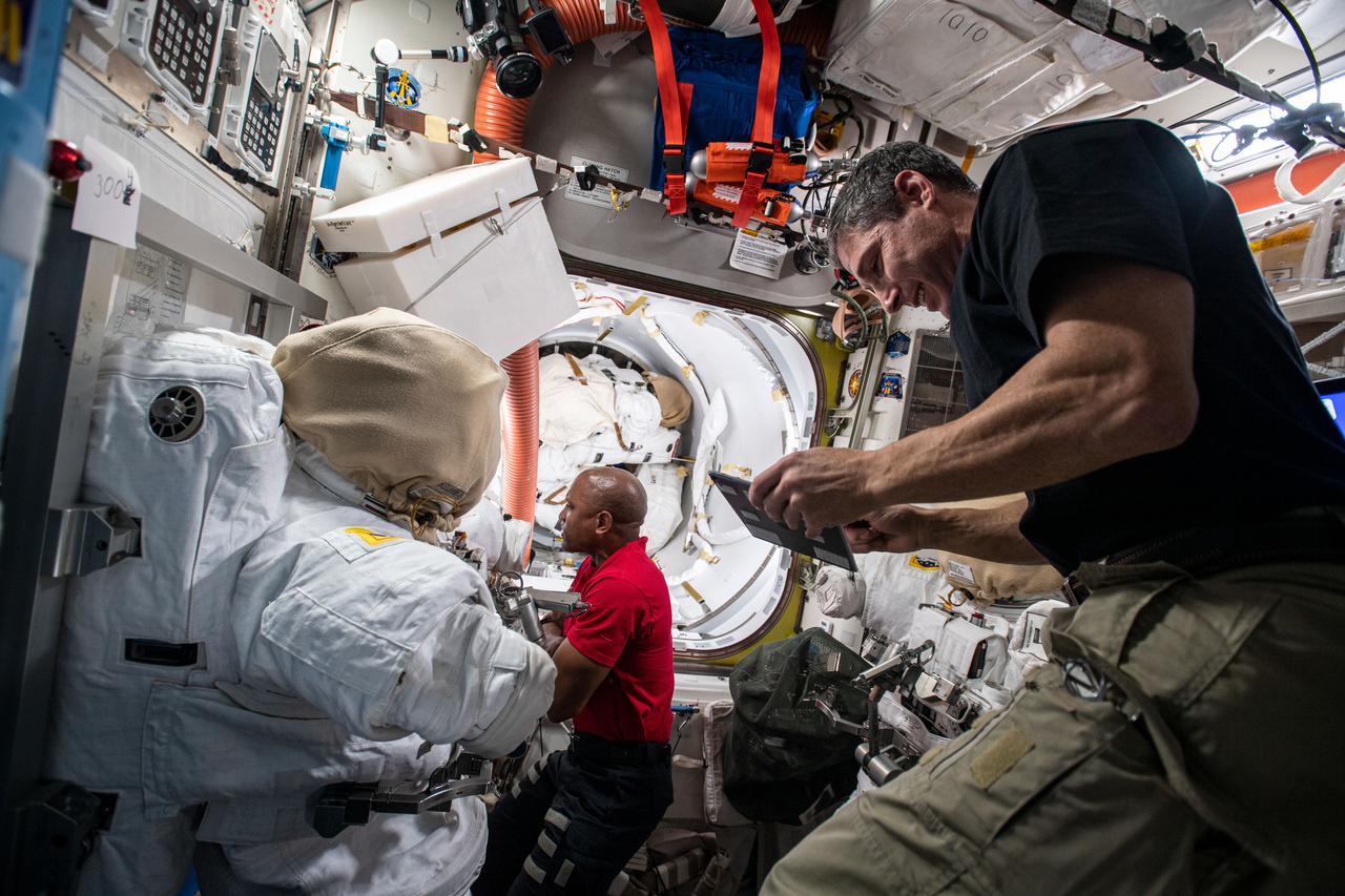 iss064e0221696 (Jan. 8, 2021) --- Flight Engineers Michael Hopkins (foreground) and Victor Glover configure tools inside the Quest airlock for planned spacewalks to continue maintenance on the outside of the International Space Station.