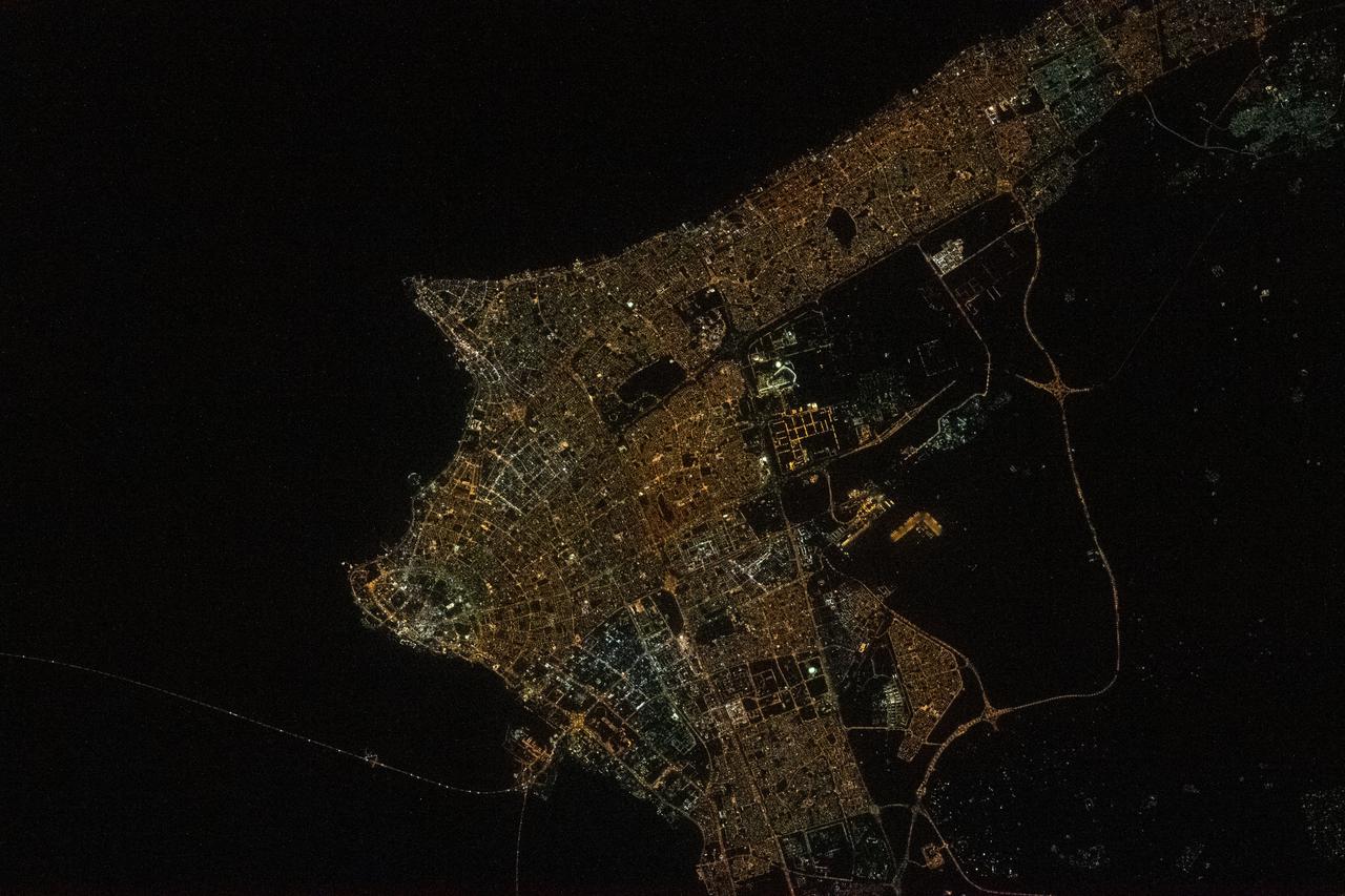 iss064e021961 (Jan. 9, 2021) --- Kuwait City is pictured during a night time pass from the International Space Station as it orbited 261 miles above the Iraq-Saudi Arabia border. Towards the bottom left, is the Sheikh Jaber Al-Ahmad Al-Sabah Causeway, the world's fourth longest road bridge at 24.5 miles, that crosses Kuwait Bay.