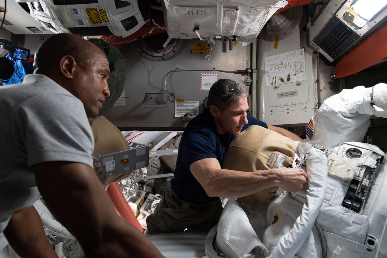 iss064e023968 (Jan. 19, 2021) --- NASA astronauts Victor Glover (left) and Michael Hopkins work on U.S. spacesuit maintenance inside the International Space Station's Quest airlock.