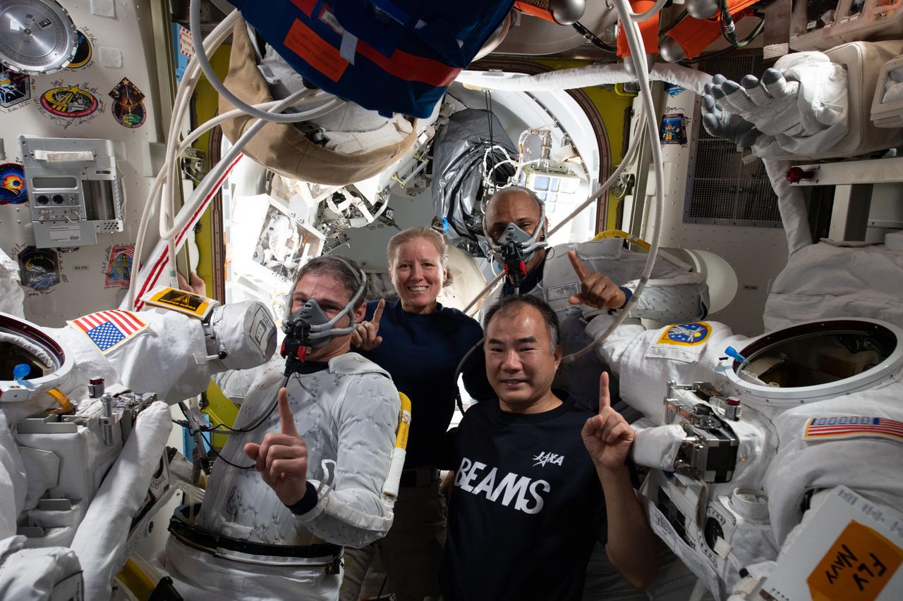 iss064e028065 (Feb. 1, 2021) --- Clockwise from bottom right are, Expedition 64 Flight Engineers and SpaceX Crew-1 members Soichi Noguchi, Michael Hopkins, Shannon Walker and Victor Glover during spacewalk preparations inside the U.S. Quest airlock. Hopkins and Glover are wearing masks breathing pure oxygen to purge nitrogen from their bodies before beginning their spacewalk. The pre-breathe protocol helps prevent a condition known as the "bends" that can occur when the body is exposed to different pressure environments.