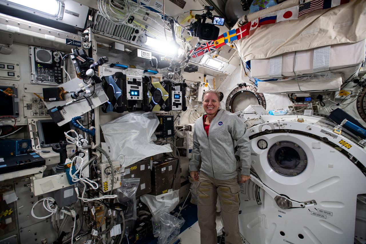 iss064e029277 (Feb. 4, 2021) --- NASA astronaut and Expedition 64 Flight Engineer Shannon Walker poses with a pair of Astrobee robotic assistants docked to their ports inside the Japanese Kibo laboratory module. The cube-shaped, toaster-sized robots are being tested for their ability to autonomously navigate and maneuver inside the orbiting lab.