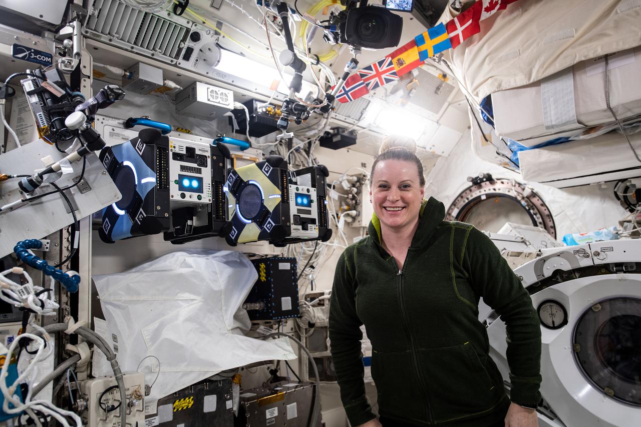 iss064e029280 (Feb. 4, 2021) --- NASA astronaut and Expedition 64 Flight Engineer Kate Rubins poses with a pair of AstroBee robotic assistants inside the Japanese Kibo laboratory module. The cube-shaped, toaster-sized robots are being tested for their ability to autonomously navigate and maneuver inside the orbiting lab.