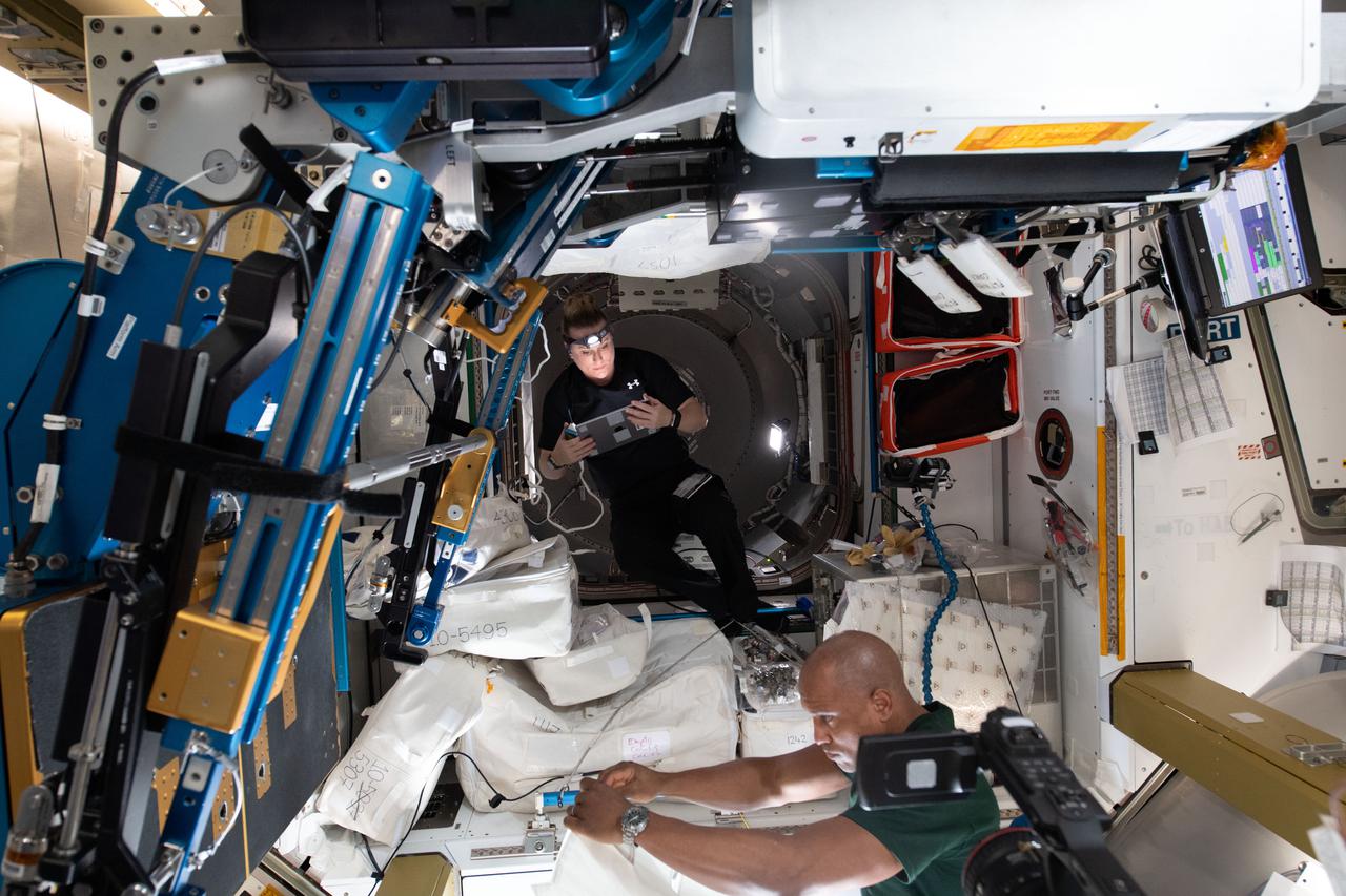iss064e031285 (Feb. 11, 2021) --- NASA astronauts and Expedition 64 Flight Engineers Kate Rubins and Victor Glover connect cables and install components during configuration work inside the newly-opened NanoRacks Bishop airlock attached to the Tranquility module. Bishop will enable more commercial research, satellite deployments, and cargo operations outside in the vacuum of space.