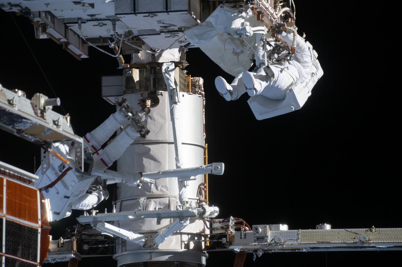 iss064e038304 (Feb. 28, 2021) --- NASA astronauts Kate Rubins (lower left) and Victor Glover (upper right) are pictured during a spacewalk to install solar array modification kits on the International Space Station. The maintenance work will support new, more powerful solar arrays that will be delivered on upcoming SpaceX Dragon cargo missions.