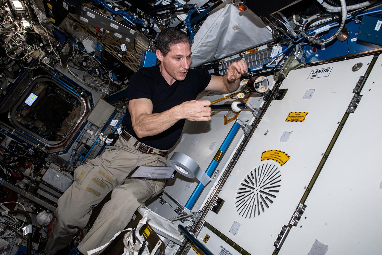 iss064e039521 (3/4/2021) --- NASA Astronaut Mike Hopkins is shown using the High school students United with NASA to Create Hardware (HUNCH) Tape Dispenser (HUNCH Tape Dispenser) aboard the International Space Station (ISS). The dispenser enables one-handed operation for crew members. Crew members regularly use tape for mundane and critical tasks, but the tape must be cut with scissors, requiring two hands. The HUNCH Tape Dispenser is expected to improve efficiency of operations and scientific research on the space station.