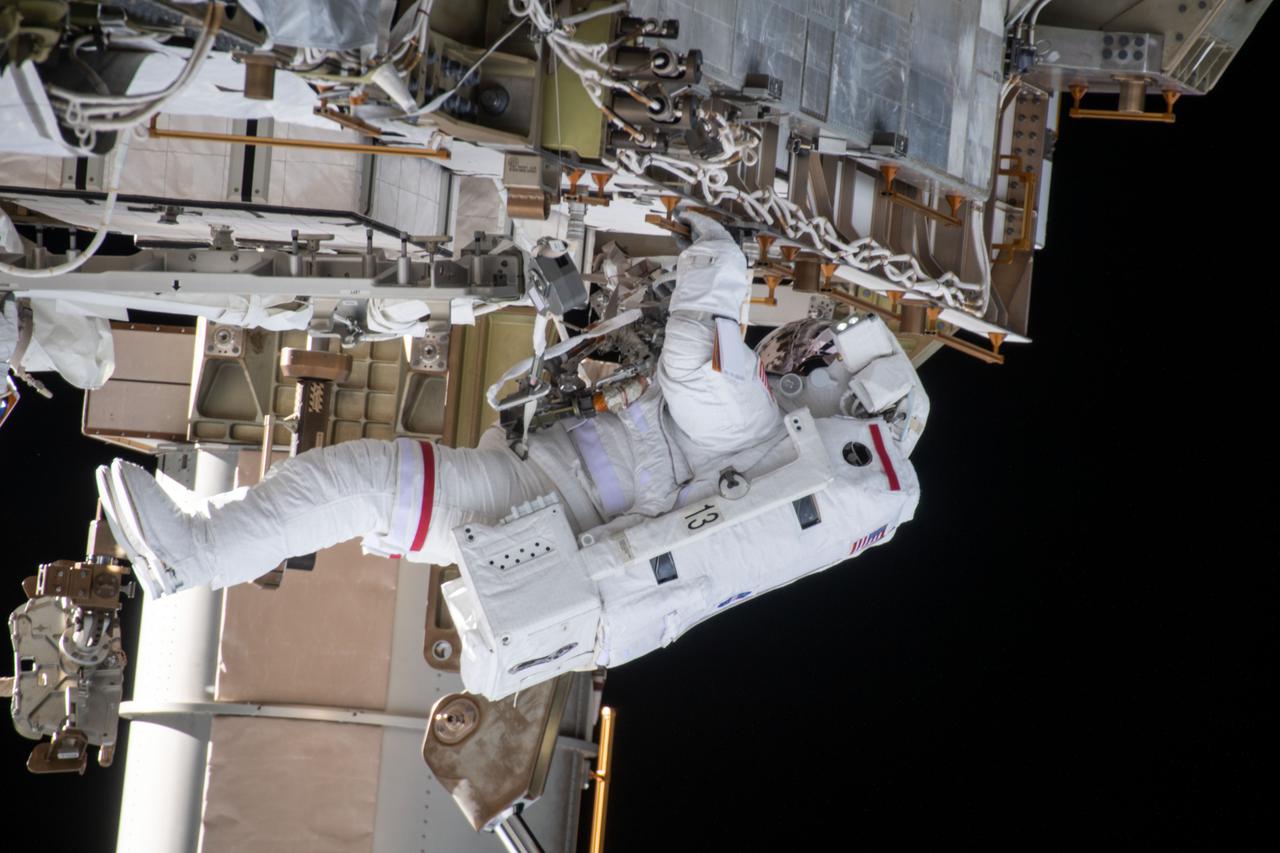iss064e039793 (March 5, 2021) --- NASA astronaut Kate Rubins (at top) is pictured during a spacewalk to install solar array modification kits to ready the International Space Station for newer, more powerful solar arrays being delivered on upcoming SpaceX Dragon cargo missions.