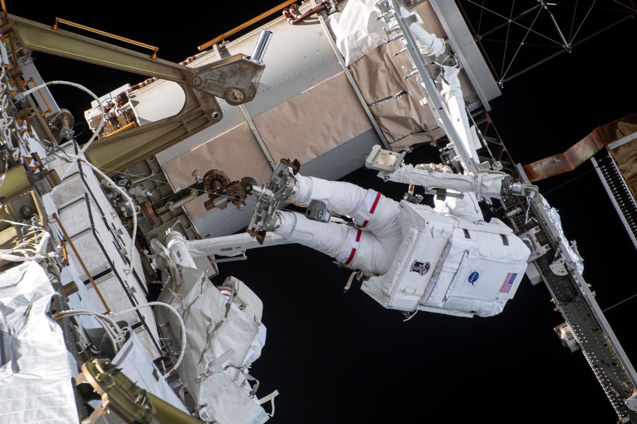 iss064e039827 (March 5, 2021) --- NASA astronaut Kate Rubins (at top) is pictured during a spacewalk to install solar array modification kits to ready the International Space Station for newer, more powerful solar arrays being delivered on upcoming SpaceX Dragon cargo missions.
