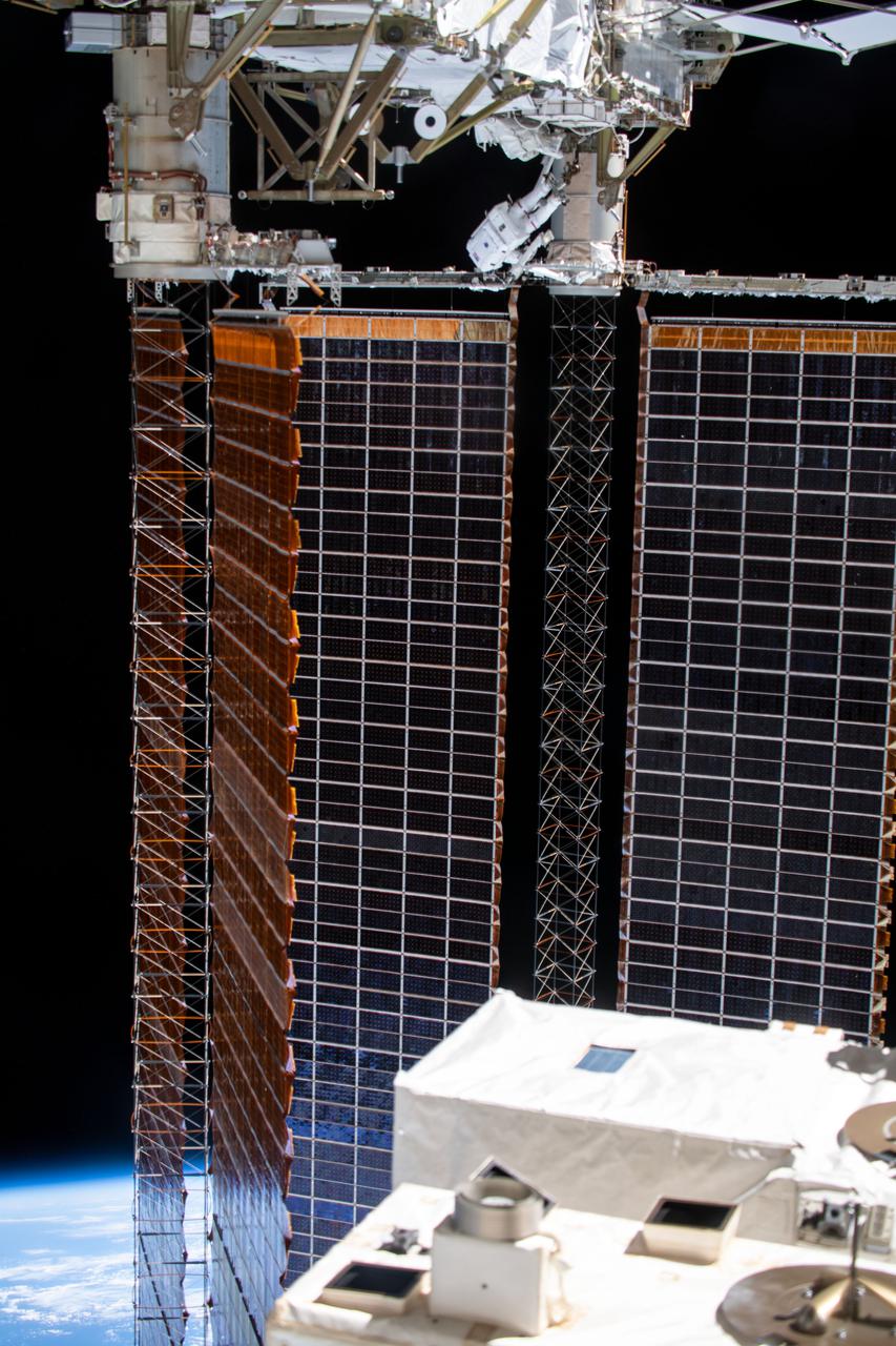 iss064e039832 (March 5, 2021) --- NASA astronaut Kate Rubins (at top) is pictured during a spacewalk to install solar array modification kits to ready the International Space Station for newer, more powerful solar arrays being delivered on upcoming SpaceX Dragon cargo missions.
