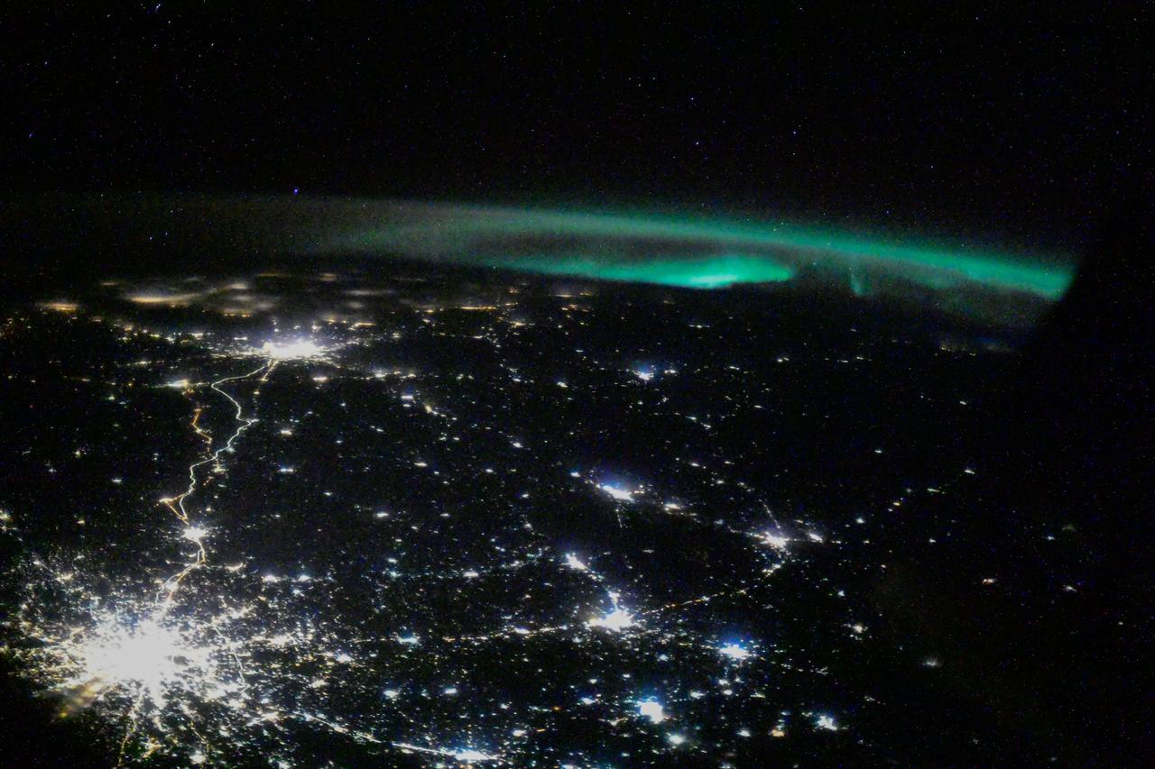 iss064e041140 (March 8, 2021) --- The city lights of Moscow and its suburbs seemingly branch out towards an aurora in this photograph taken from the International Space Station as it orbited 263 miles above the Volga River in Russia. Credit: Roscosmos
