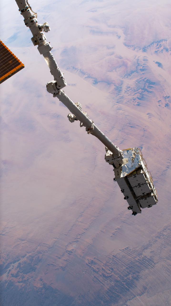 iss064e041189 (March 11, 2021) --- The Canadarm2 robotic arm, with an external pallet packed with old nickel-hydrogen batteries in its grip, is pictured as the International Space Station orbited 260 miles above the Sahara in the African nation of Chad. Mission controllers in Houston later commanded the Canadarm2 to release the external pallet into space where it will orbit Earth between two to four years before burning up harmlessly in the atmosphere. The batteries were removed during previous spacewalks and replaced with newer lithium-ion batteries to continue powering the station's systems.
