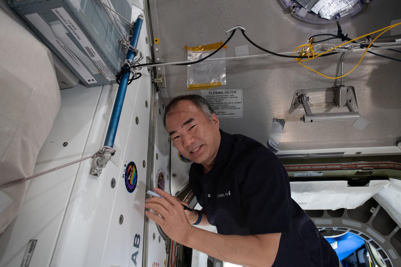 iss064e053413 (April 6, 2021) --- Japan Aerospace Exploration Agency astronaut and Expedition 64 Flight Engineer Soichi Noguchi applies his signature to the Unity module's vestibule that leads to the Cygnus space freighter from Northrop Grumman.