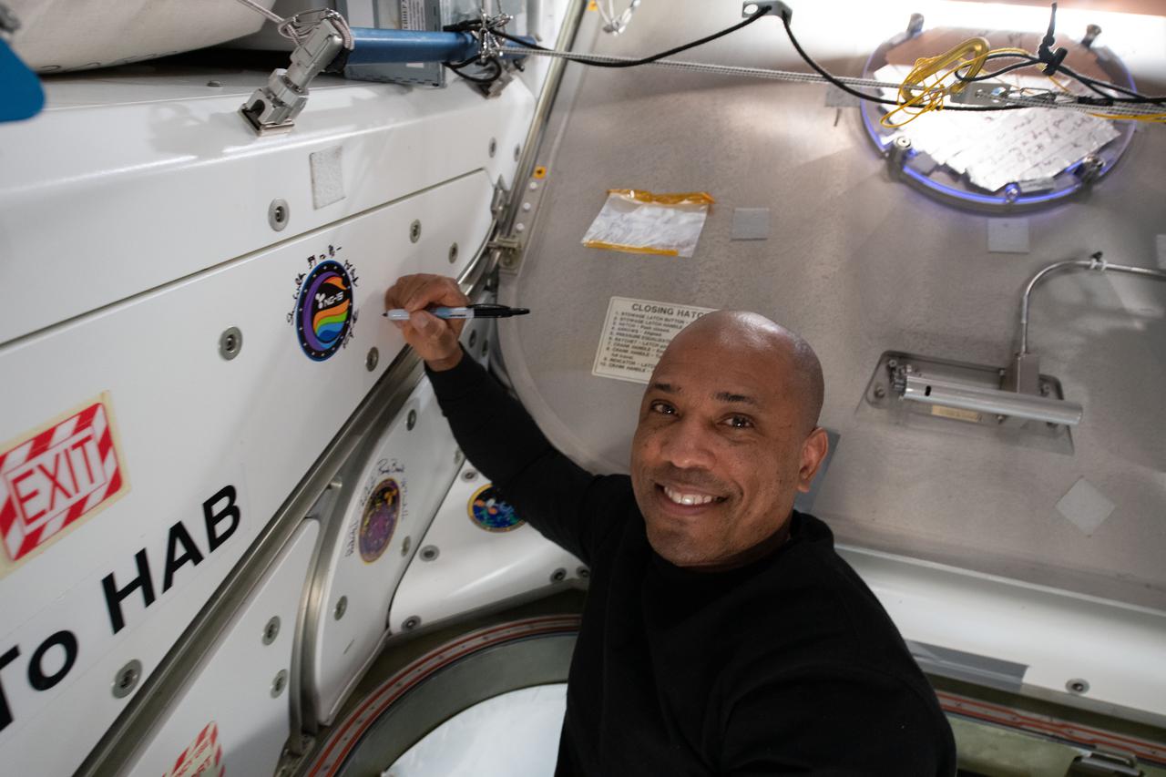 iss064e053421 (April 6, 2021) --- NASA astronaut and Expedition 64 Flight Engineer Victor Glover applies his signature to the Unity module's vestibule that leads to the Cygnus space freighter from Northrop Grumman.