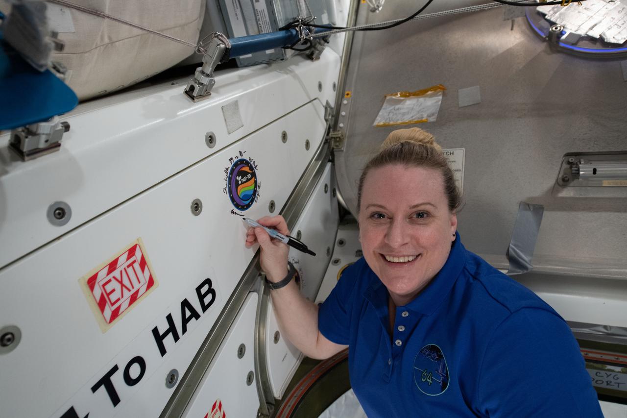 iss064e053423 (April 6, 2021) --- NASA astronaut and Expedition 64 Flight Engineer Kate Rubins applies her signature to the Unity module's vestibule that leads to the Cygnus space freighter from Northrop Grumman.