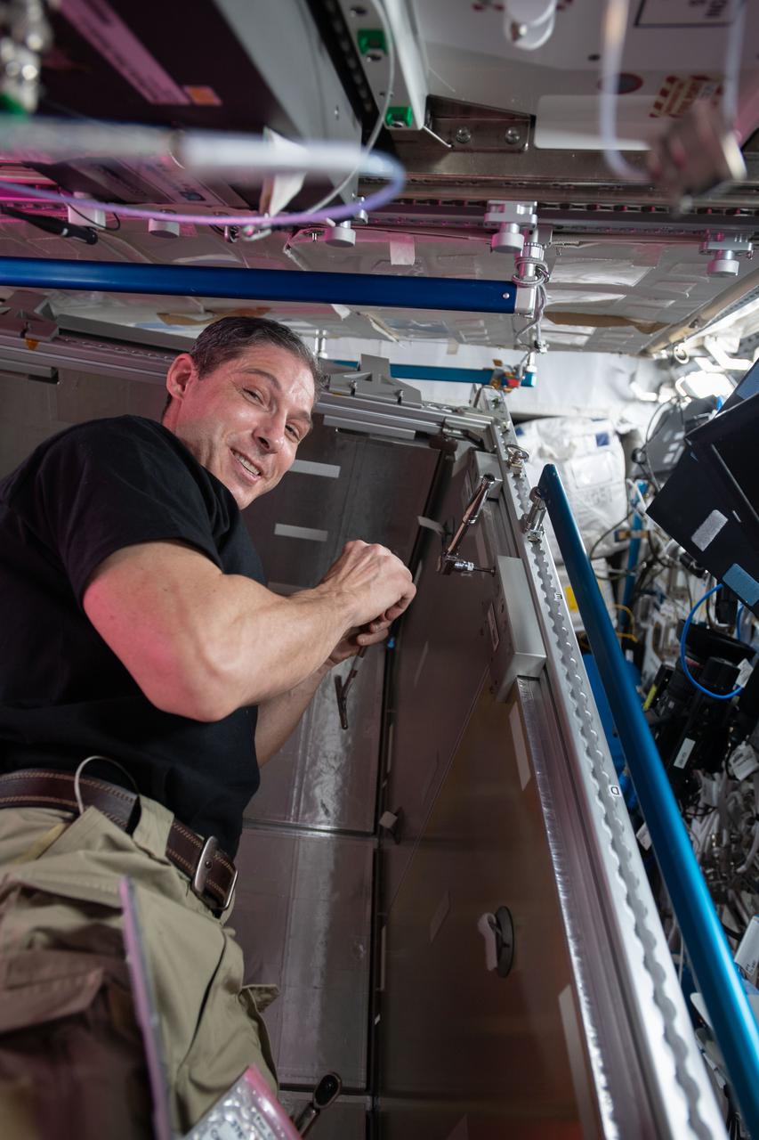 iss064e053494 (April 7, 2021) --- NASA astronaut and Expedition 64 Flight Engineer Michael Hopkins installs temporary sleeping quarters inside the Columbus laboratory module from the European Space Agency. The new Crew Alternate Sleep Accommodation, which can also be converted to a cargo storage rack, will allow extra space for the short period when up to 11 crew members will be occupying the International Space Station in April.