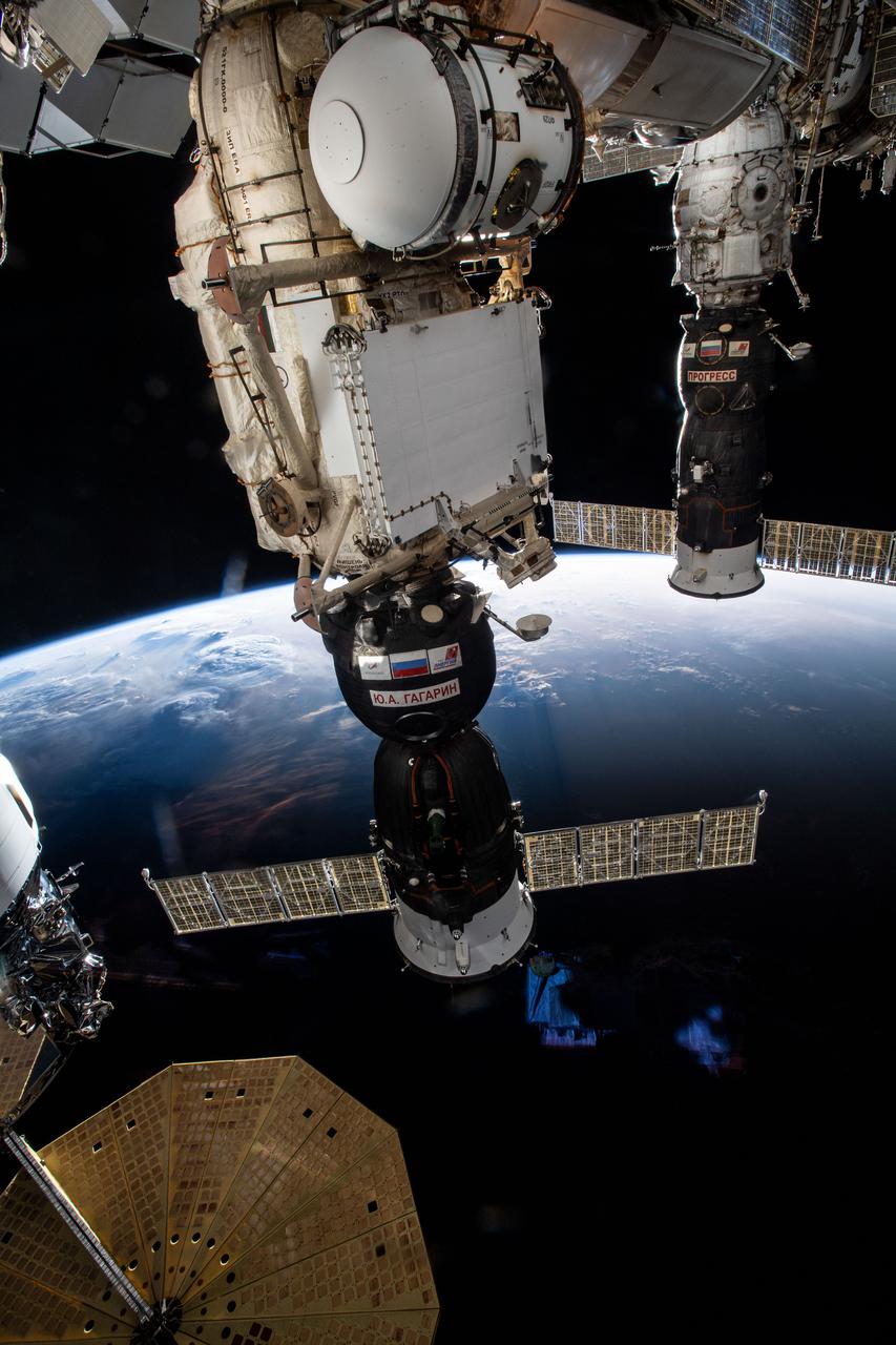 iss064e057795 (April 12, 2021) --- Two spaceships are pictured attached to the International Space Station as it flies into an orbital sunset 260 miles above Nigeria. From left, are the Soyuz MS-18 crew ship docked to the Rassvet module and the Progress 77 cargo craft docked to the Pirs docking compartment. A portion of the Northrop Grumman space freighter, with one of its prominent cymbal-shaped solar arrays, is pictured at lower left.