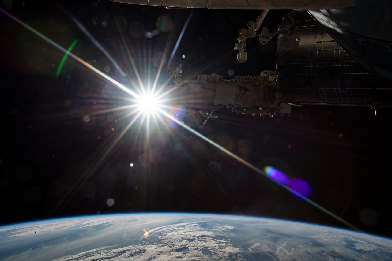 iss065e028811 (May 9, 2021) --- The sun's rays beam into the camera as the International Space Station orbited 265 miles above Kazakhstan. In the top foreground, is a portion of the Japanese Kibo laboratory module, Kibo's robotic arm and its Exposed Facility that hosts external space experiments.