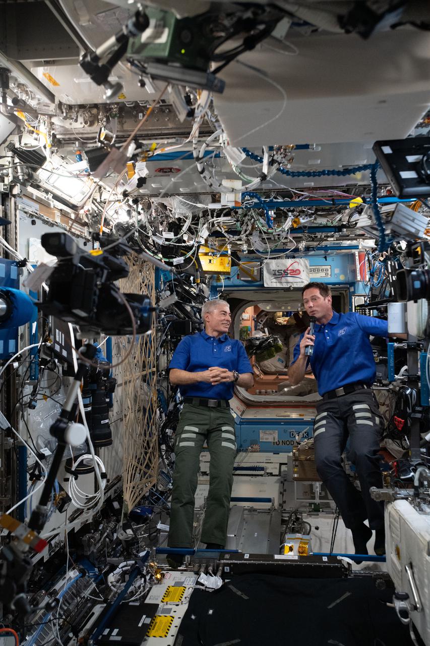 iss065e034014 (May 12, 2021) --- Expedition 65 Flight Engineers (from left) Mark Vande Hei of NASA and Thomas Pesquet of ESA (European Space Agency) are pictured inside the U.S. Destiny laboratory module participating in an interview with a journalist on the ground.