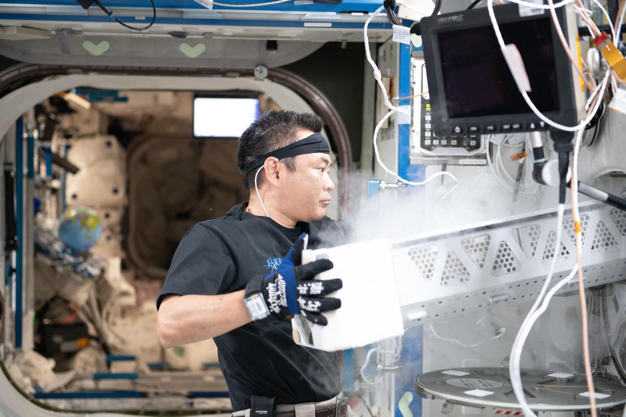 iss065e047574 (May 19, 2021) --- Expedition 65 Commander Akihiko Hoshide of the Japan Aerospace Exploration Agency stows samples inside a science freezer, also known as the Minus Eighty-Degree Laboratory Freezer for ISS (MELFI).