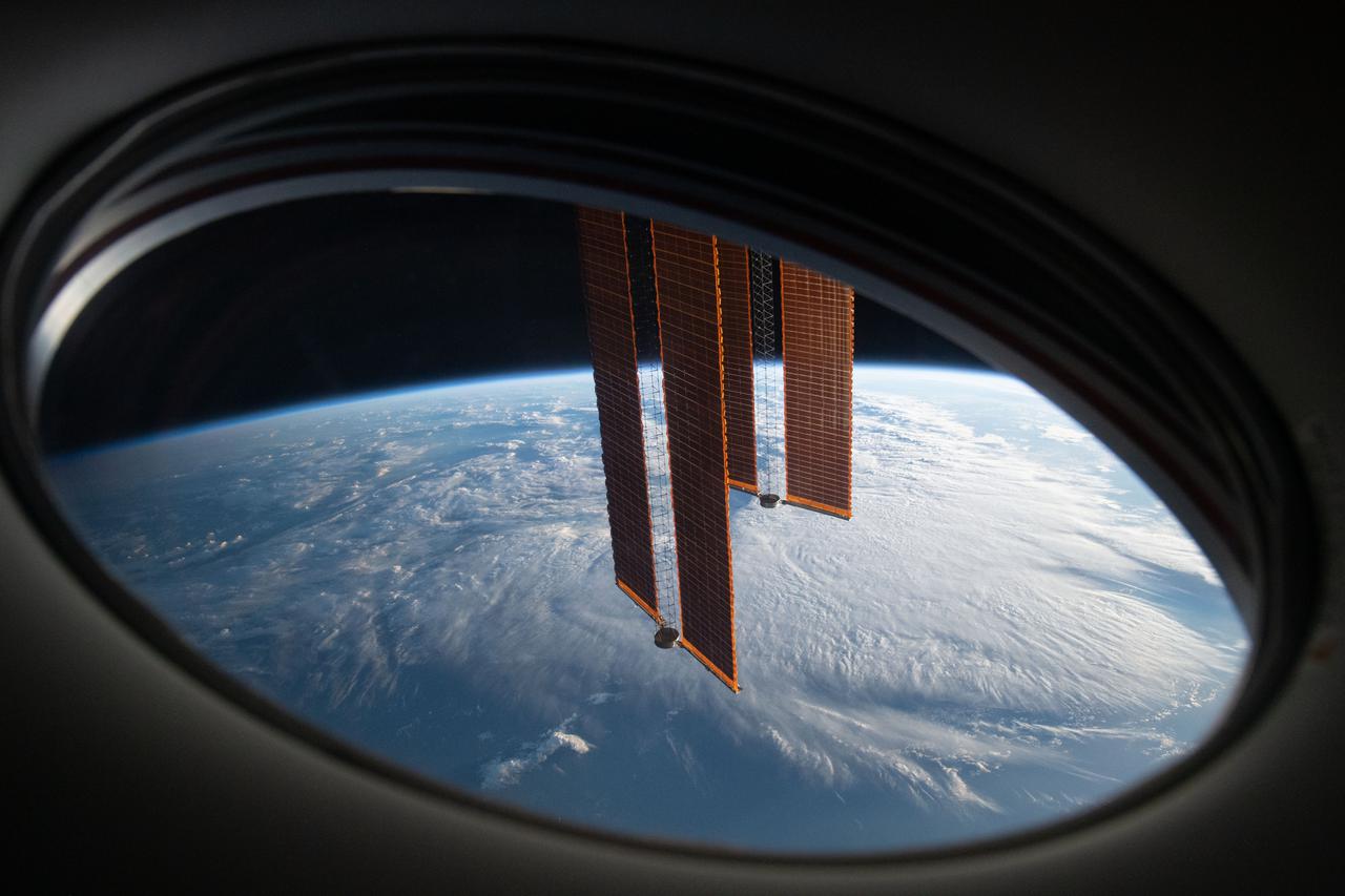 iss065e049854 (May 20, 2021) --- In this view from a window aboard the SpaceX Crew Dragon Endeavour, a pair of the International Space Station's main solar arrays drape across the Earth's horizon as the orbital lab soared 271 miles above the south Atlantic in between Argentina and South Africa.