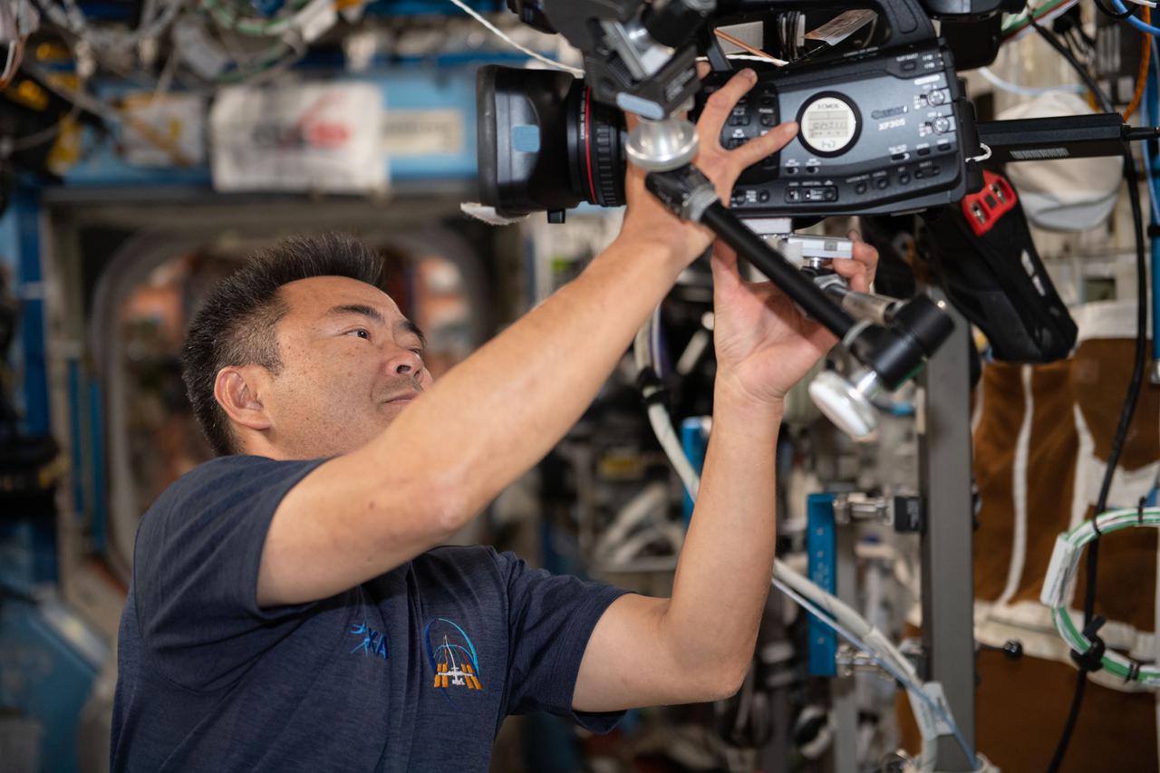 iss065e073924 (May 26, 2021) --- Expedition 65 Commander Akihiko Hoshide of the Japan Aerospace Exploration Agency sets up a video camera to record crew member activities aboard the International Space Station.