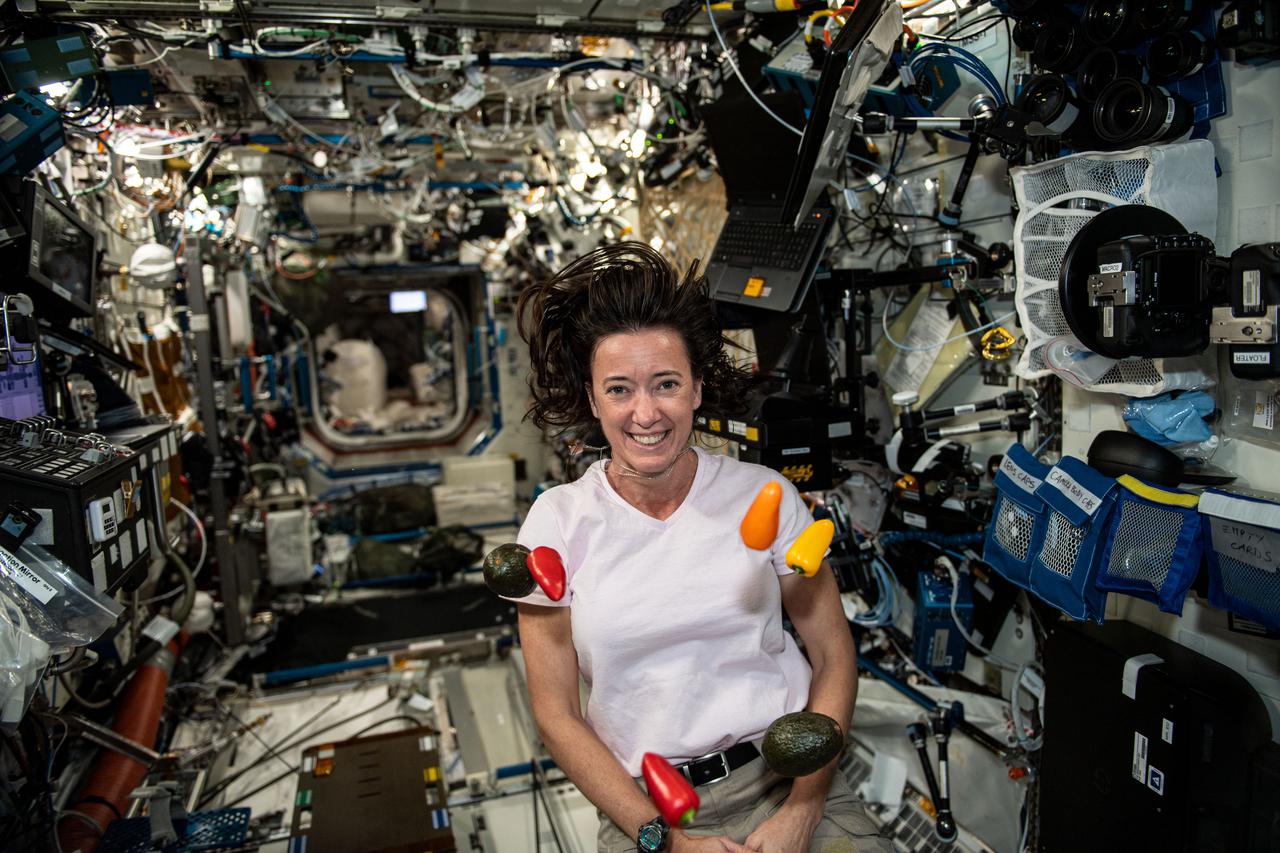 iss065e092717 (June 5, 2021) --- NASA astronaut and Expedition 65 Flight Engineer Megan McArthur seemingly juggles fresh peppers and avocados that were just delivered to the International Space Station aboard the SpaceX Crew Dragon resupply ship.