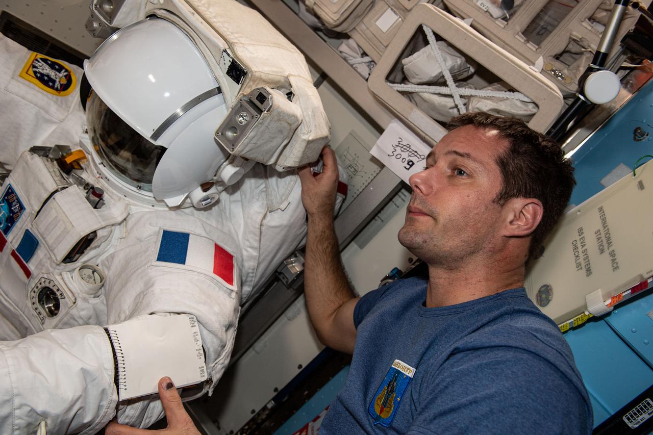 iss065e144290 (June 14, 2021) --- Expedition 65 Flight Engineer Thomas Pesquet of ESA (European Space Agency) checks his U.S. spacesuit ahead of a spacewalk to begin installing roll out solar arrays on the International Space Station's Port-6 truss structure.