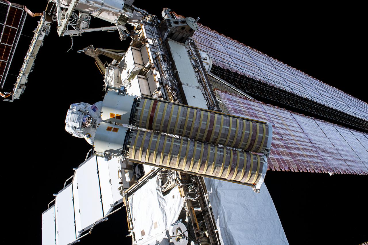 iss065e145318 (June 25, 2021) --- NASA spacewalker Shane Kimbrough carries the second roll out solar array toward the International Space Station's Port-6 truss structure where he and fellow spacewalker Thomas Pesquet of ESA (European Space Agency) would install it.