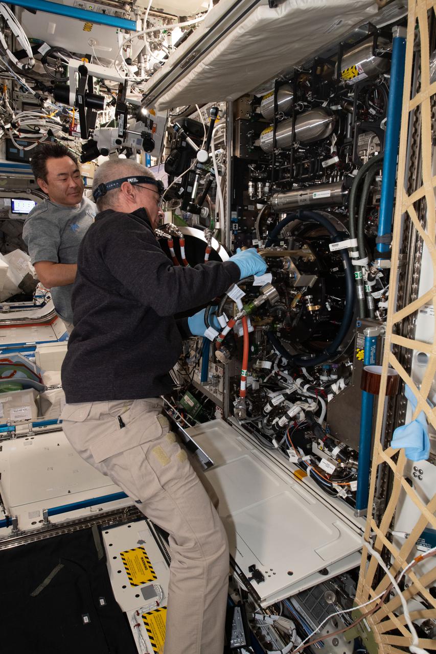iss065e156020 (July 2, 2021) --- Expedition 65 astronauts Commander Akihiko Hoshide (rear) and Flight Engineer Mark Vande Hei replace components inside the Combustion Integrated Rack that enables safe research into microgravity's effects on flames, fuel and soot aboard the International Space Station's U.S. Destiny laboratory module.