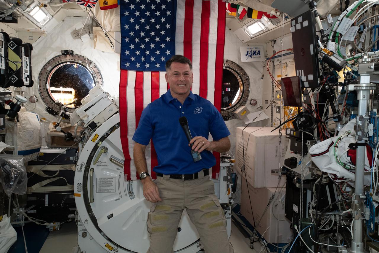 iss065e156102 (July 4, 2021) --- NASA astronaut and Expedition 65 Flight Engineer Shane Kimbrough is pictured inside the Kibo laboratory module with the U.S. flag behind him on the July the 4th Independence Day holiday.