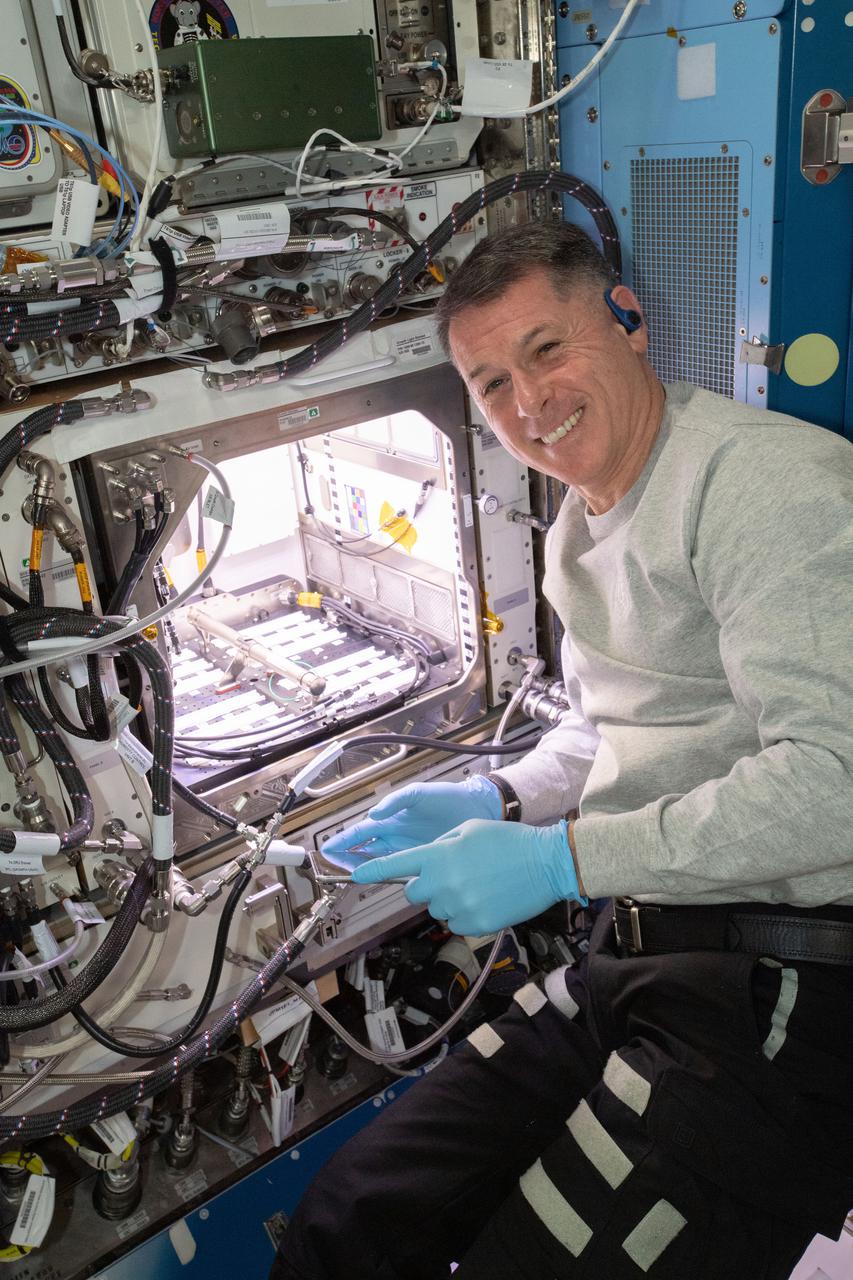 (iss065e163671) July 12, 2021 --- NASA astronaut and Expedition 65 Flight Engineer Shane Kimbrough inserts a device called a science carrier into the Advanced Plant Habitat (APH), which contains 48 Hatch chile pepper seeds NASA started growing on July 12, 2021 as part of the Plant Habitat-04 experiment. Astronauts on station and a team of researchers at Kennedy will work together to monitor the peppers’ growth for about four months before harvesting them. This will be one of the longest and most challenging plant experiments attempted aboard the orbital lab.