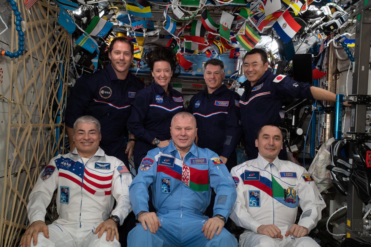 iss065e166107 (July 10, 2021) --- The seven-member Expedition 65 crew gets together for a portrait aboard the International Space Station. In the front row from left are, flight engineers Mark Vande Hei, Oleg Novitskiy and Pyotr Dubrov. In the back are, flight engineers Thomas Pesquet, Megan McArthur and Shane Kimbrough with Commander Akihiko Hoshide.