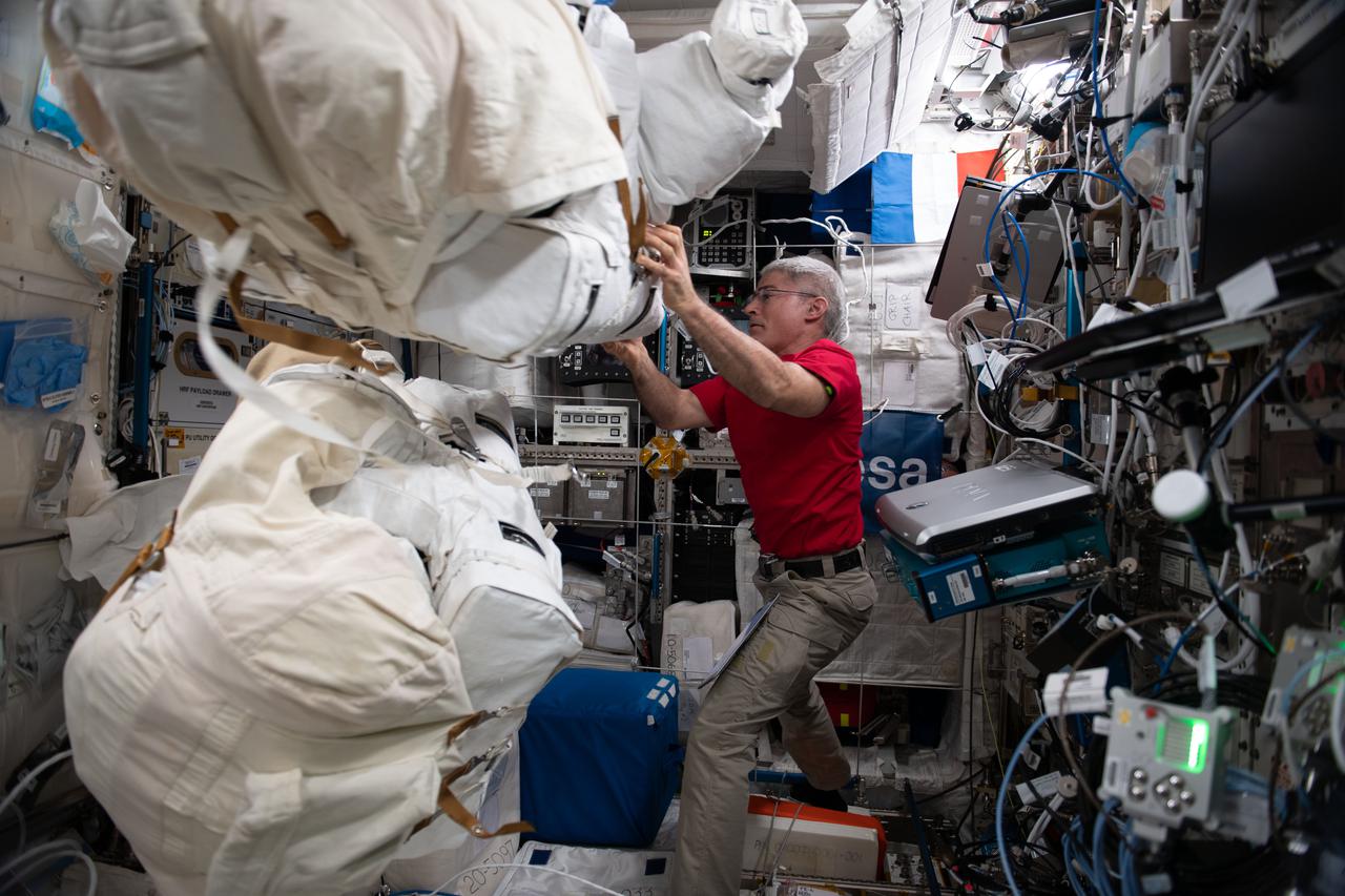 iss065e206853 (July 27, 2021) --- NASA astronaut and Expedition 65 Flight Engineer Mark Vande Hei unpacks U.S. spacesuits before installing high definition camera assemblies on the suits.