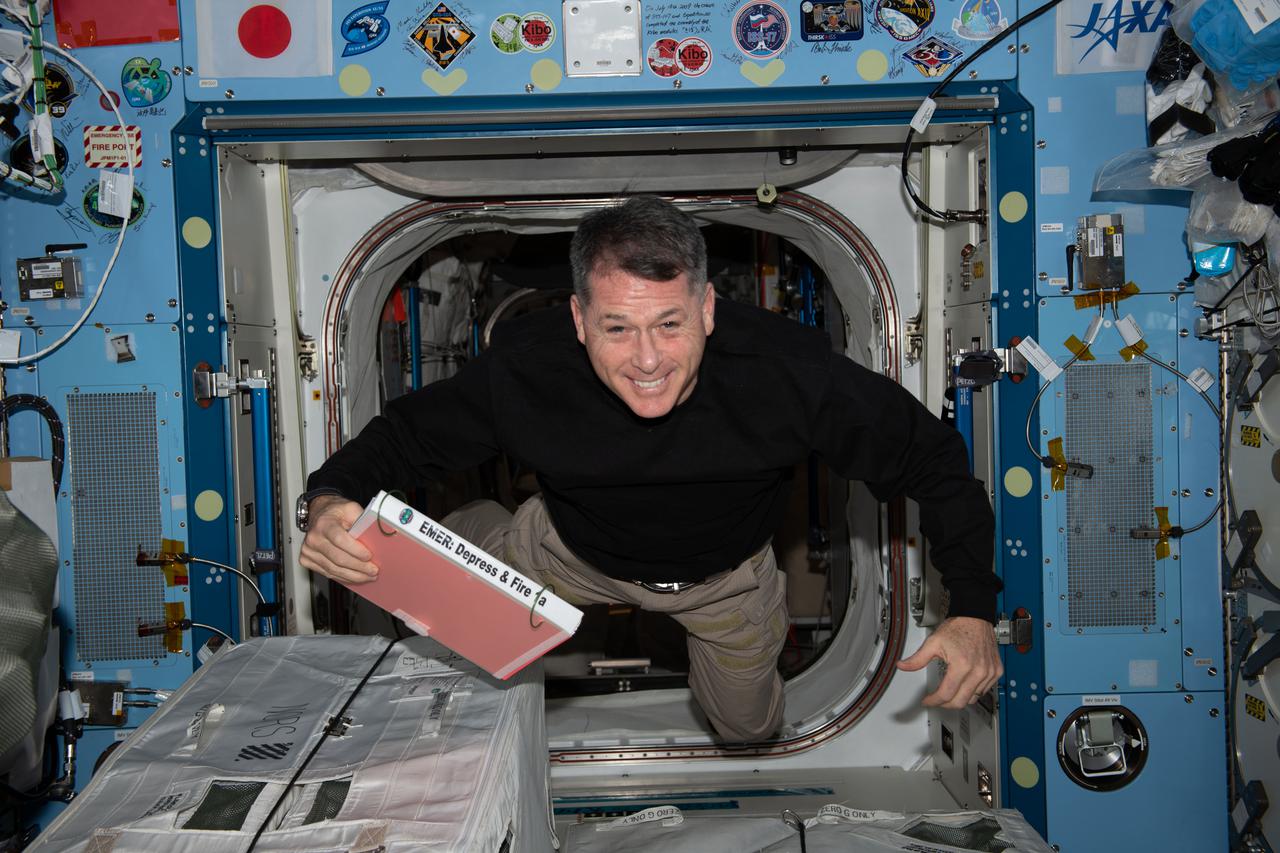 iss065e257442 (Aug. 17, 2021) --- NASA astronaut and Expedition 65 Flight Engineer Shane Kimbrough maneuvers through the International Space Station carrying an emergency manual describing procedures the crew would take in the unlikely event of a depressurization or a fire aboard the orbiting lab.