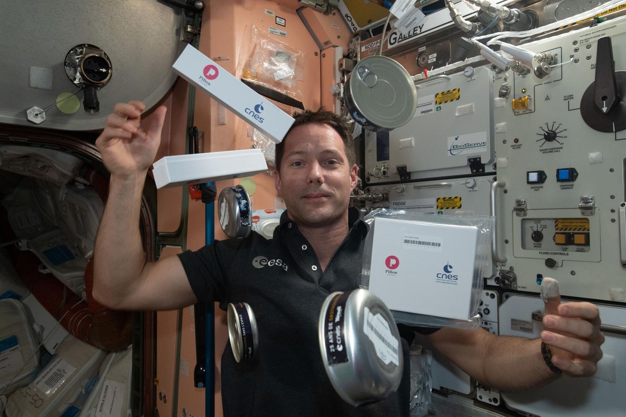 iss065e281904 (Aug. 18, 2021) --- Flight Engineer Thomas Pesquet of ESA (European Space Agency) seemingly juggles food and snack containers from CNES, France's National Centre for Space Studies.