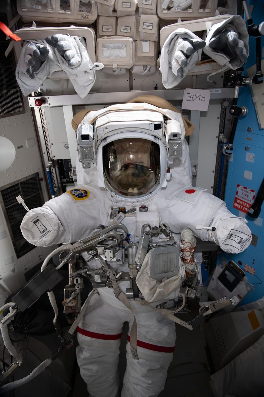 iss065e282008 (Aug. 22, 2021) --- An empty U.S. spacesuit bearing a patch of the Japanese flag on the left shoulder is pictured inside the International Space Station's Quest airlock. Expedition 65 Commander Akihiko Hoshide wore this spacesuit during a spacewalk on Sept. 12 with Flight Engineer Thomas Pesquet of ESA (European Space Agency). Stowed above the spacesuit are the gloves that the astronauts wore.