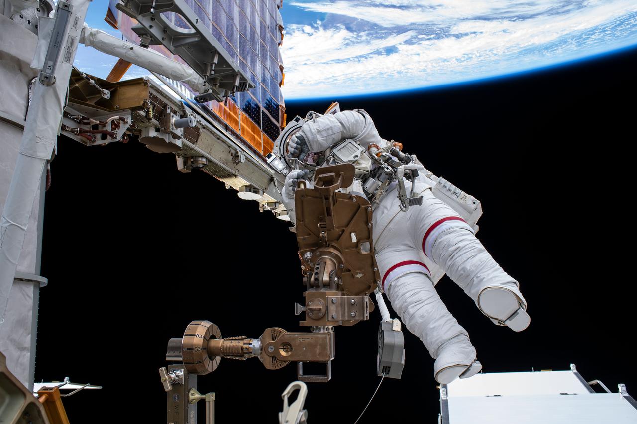 iss065e376087 (Sept. 12, 2021) --- Astronaut Akihiko Hoshide of the Japan Aerospace Exploration Agency (JAXA) works to install a modification kit on the International Space Station's Port-4 truss structure during a spacewalk that lasted six hours and 54 minutes. The orbiting lab was 263 miles above the southern Atlantic Ocean off the coast of Argentina at the time of this photograph taken by ESA (European Space Agency) astronaut Thomas Pesquet.