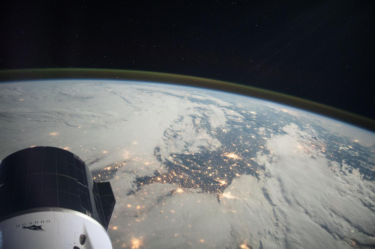 iss065e389357 (Sept. 19, 2021) --- A portion of the SpaceX Cargo Dragon vehicle is pictured at lower left as the International Space Station orbited 264 miles above northern France. The long-exposure photograph also reveals Earth's atmospheric glow and stars above the horizon.